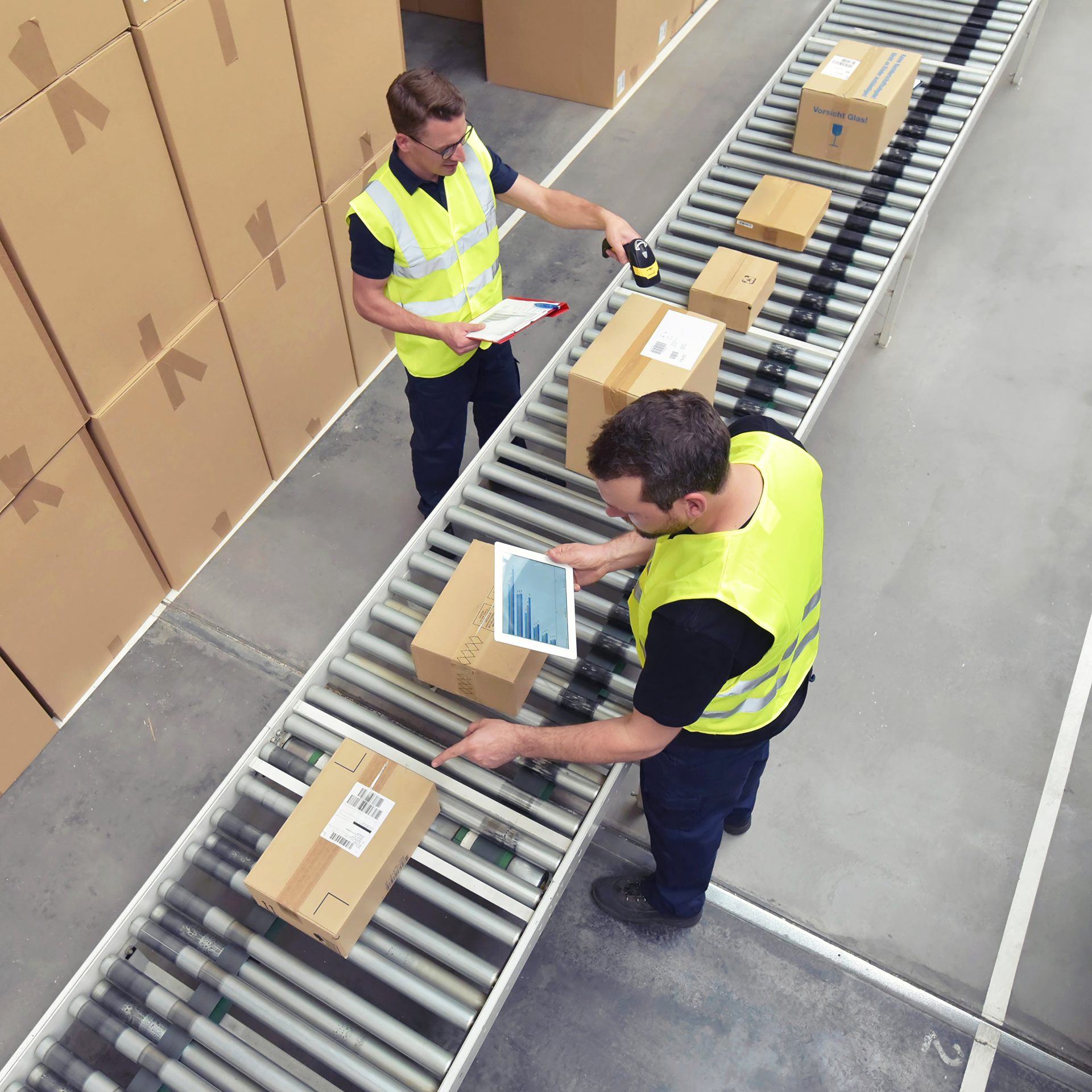 Two workers sorting boxes and holding tablets and scanners in the warehousing industry