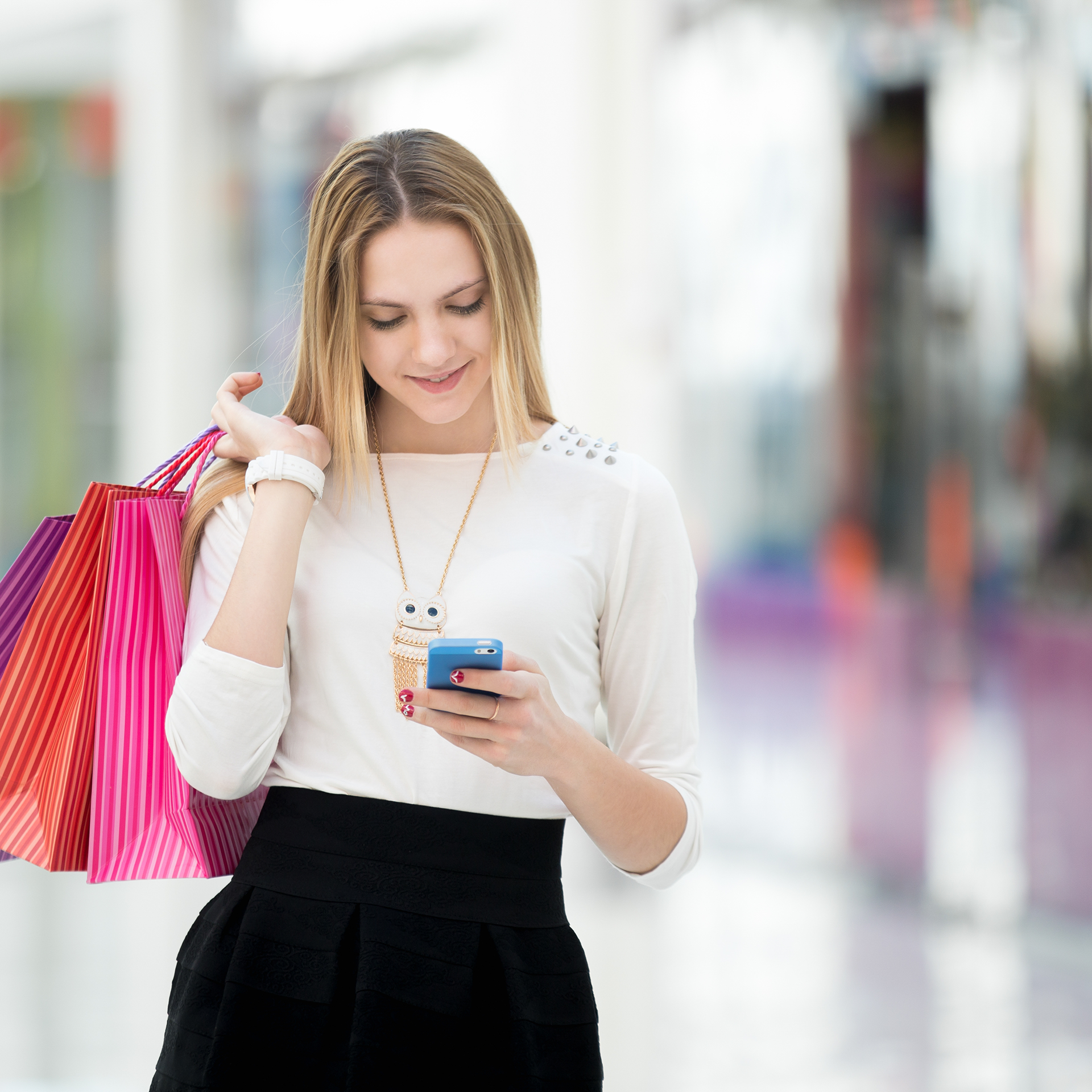 A woman holding shopping bags and using her phone