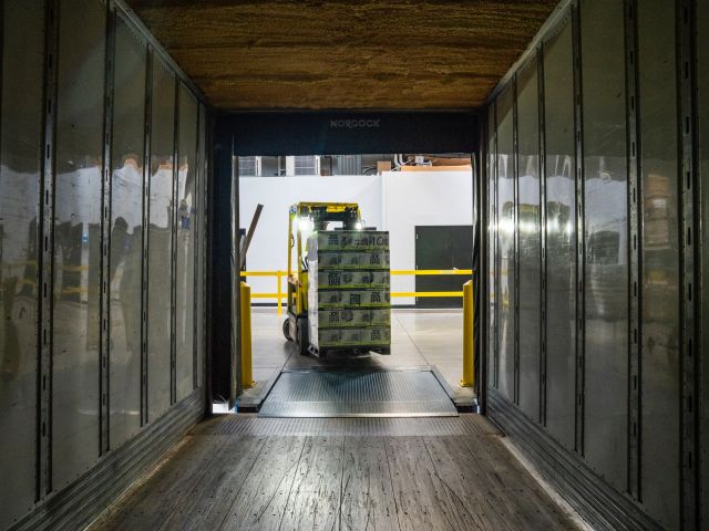 A forklift carrying a pallet of goods into a truck