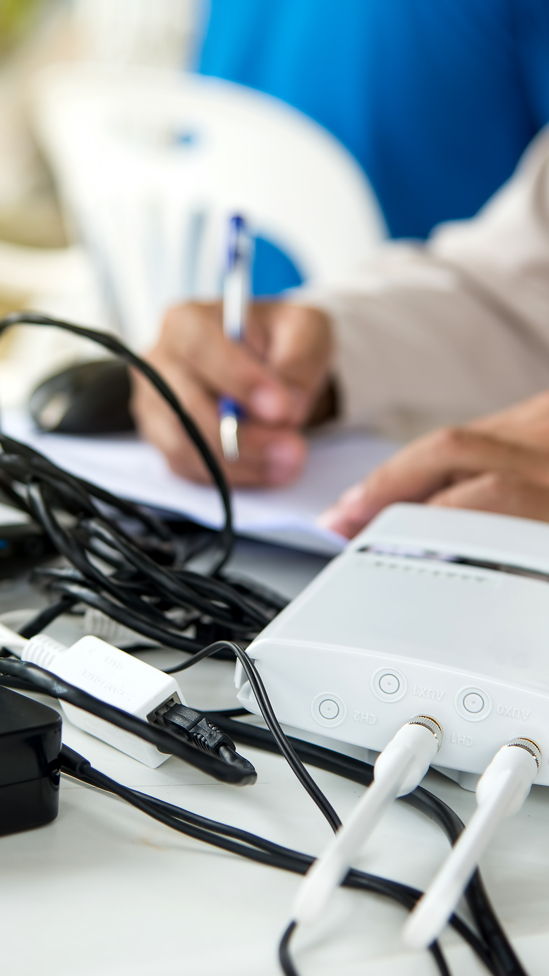 A white router and a man working on paper in the background for WiFi Services